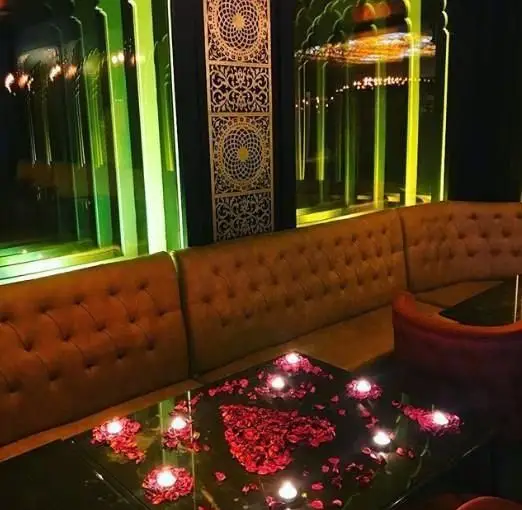 فضای رمانتیک و دنج کافی شاپ جحینا با دکوراسیون شیک، میز مزین به گلبرگ‌های رز قرمز و شمع‌های روشن برای لحظاتی خاص و به یادماندنی.