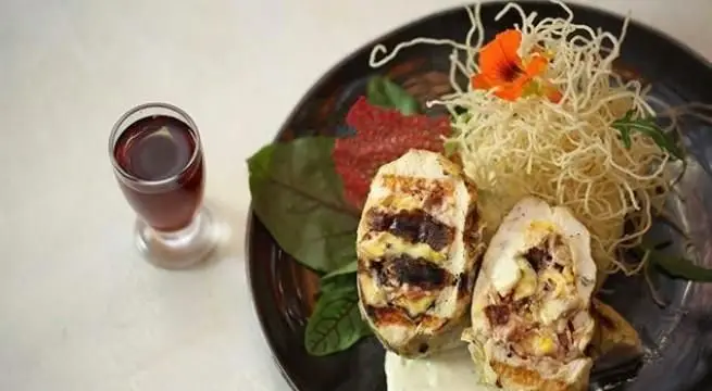 نمایی از یک غذای خاص در کافی شاپ جحینا: رول مرغ شکم‌پر با گریل، نودل کریسپی، سبزیجات تازه و نوشیدنی خنک روی میز.