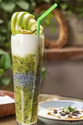 نوشیدنی اسموتی کیوی و تخم شربتی خنک و لذیذ در کافی شاپ ایوان، همراه با لایه ماست و تکه‌های کیوی تازه، انتخابی عالی برای تابستان.