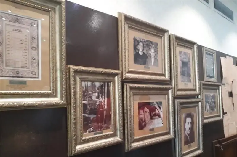 دیوار دکور رستوران ایرانی رفتاری با قاب‌های طلایی و عکس‌های تاریخی خانوادگی و اسناد قدیمی، فضایی سنتی و گرم را به تصویر می‌کشد.