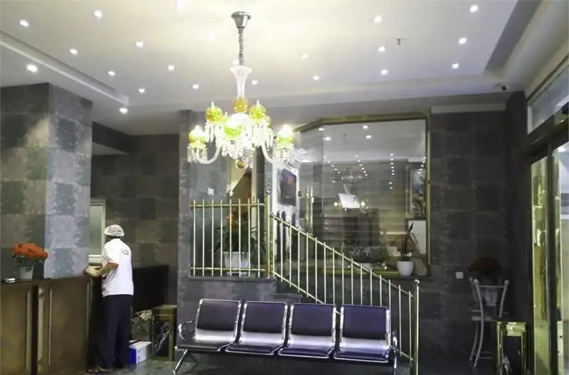نمای داخلی رستوران ایرانی رفتاری: لابی شیک با لوستر کریستالی، میز پذیرش، صندلی‌های انتظار و پله‌های با نرده طلایی.