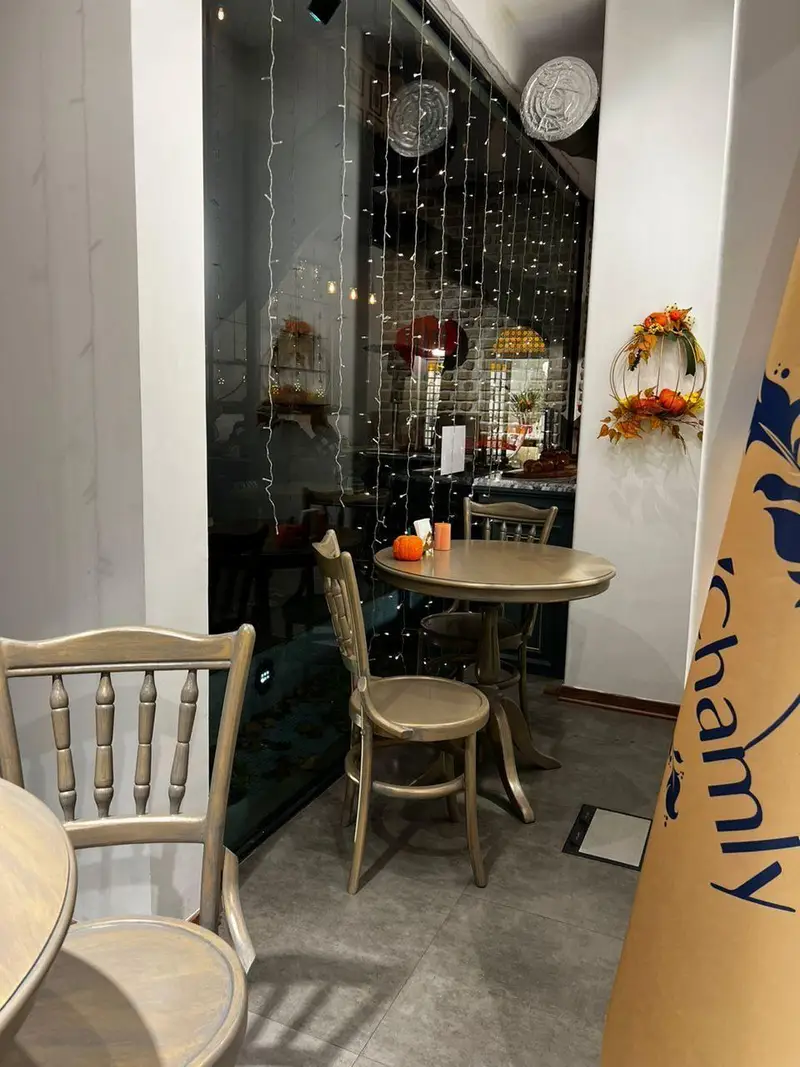 فضای داخلی دنج و زیبای کافه و رستوران چوکوچاملی با میز و صندلی چوبی، نورپردازی دلپذیر و دکوراسیون پاییزی مدرن و شیک.