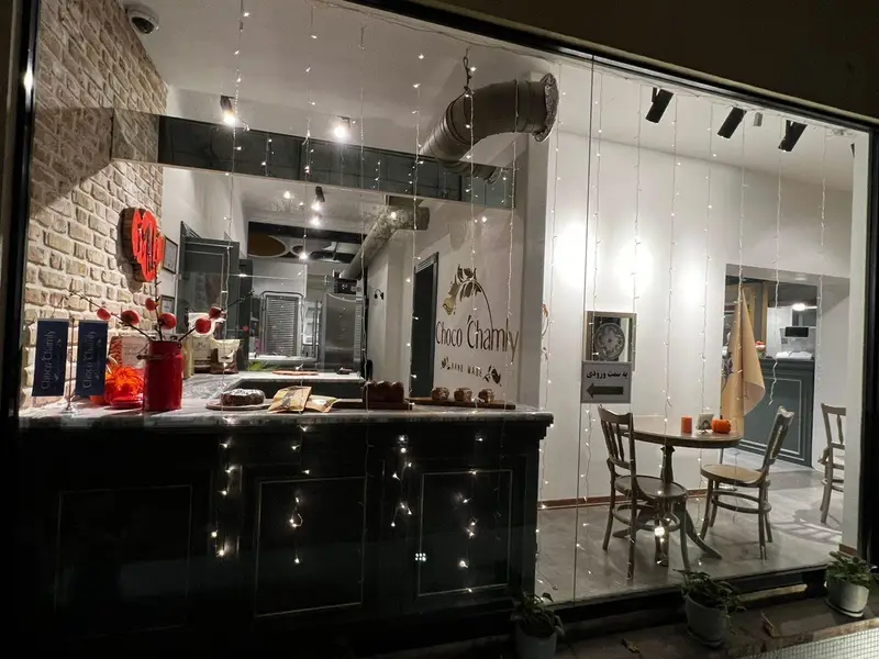 ویترین شبانه فروشگاه چوکوچاملی با نمایش محصولات شکلاتی و شیرینی، دکوراسیون جذاب و نورپردازی گرم و دعوت‌کننده.