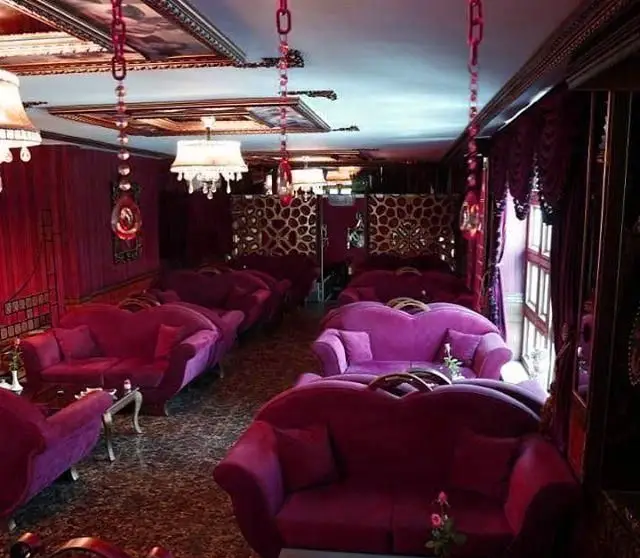 فضای داخلی جذاب و لوکس کافی شاپ ساقدوش با ردیف‌هایی از مبلمان راحتی مخملی بنفش و دکوراسیون مجلل و نورپردازی گرم، مکانی آرام.