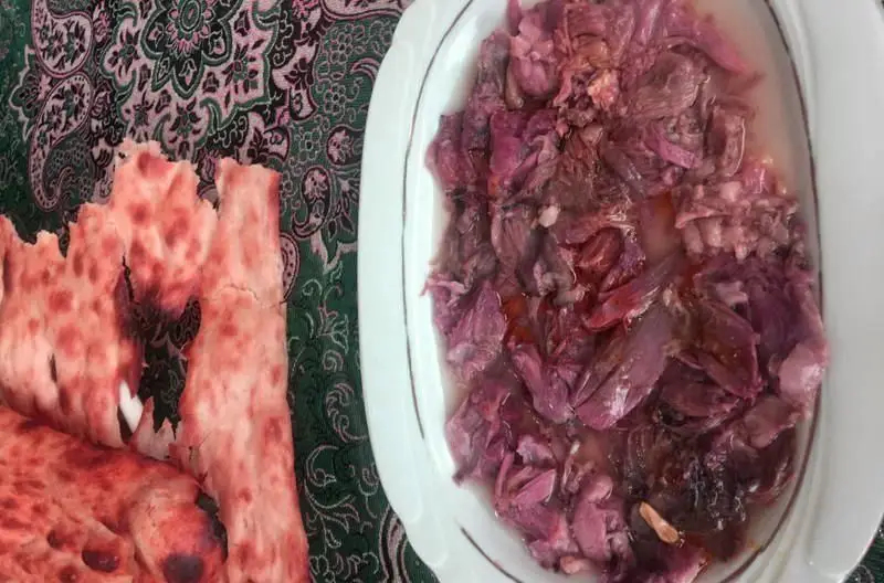 غذای سنتی و لذیذ طباخی بره ناقلا: دیسی از آبگوشت یا خورشت گوشت بره با نان گرم ایرانی، سرو شده بر روی سفره‌ای طرح‌دار.