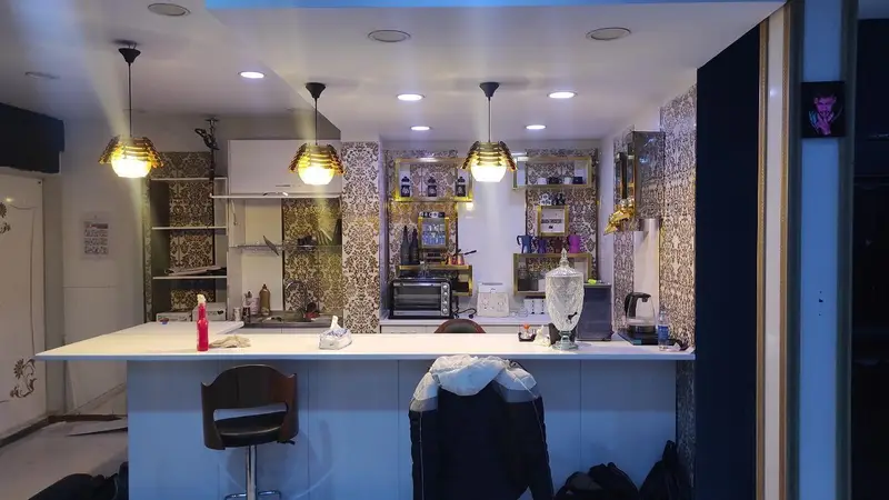 نمایی از دکوراسیون داخلی کافه گیم اسپارت با میز بار سفید، نورپردازی مدرن و دیوارپوش طرح‌دار، محیطی دنج برای بازی و دورهمی.