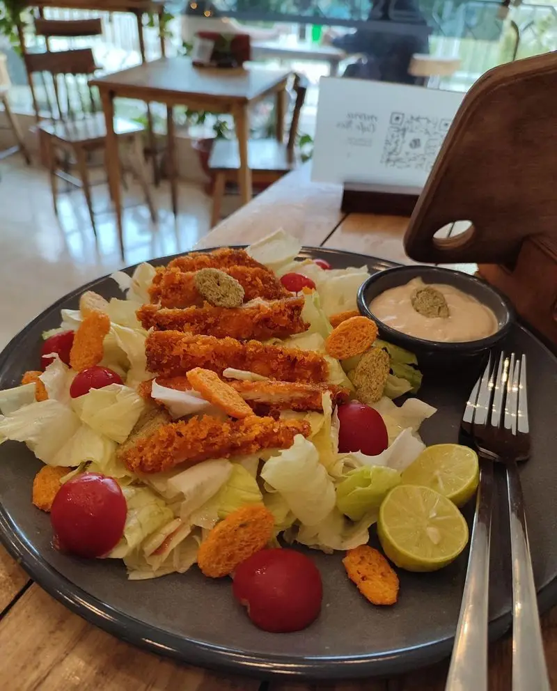 نمایی نزدیک از سالاد مرغ سوخاری ترد و آبدار کافه نار با گوجه‌گیلاسی، لیمو و سس مخصوص. مناسب برای نهار یا شام سبک.