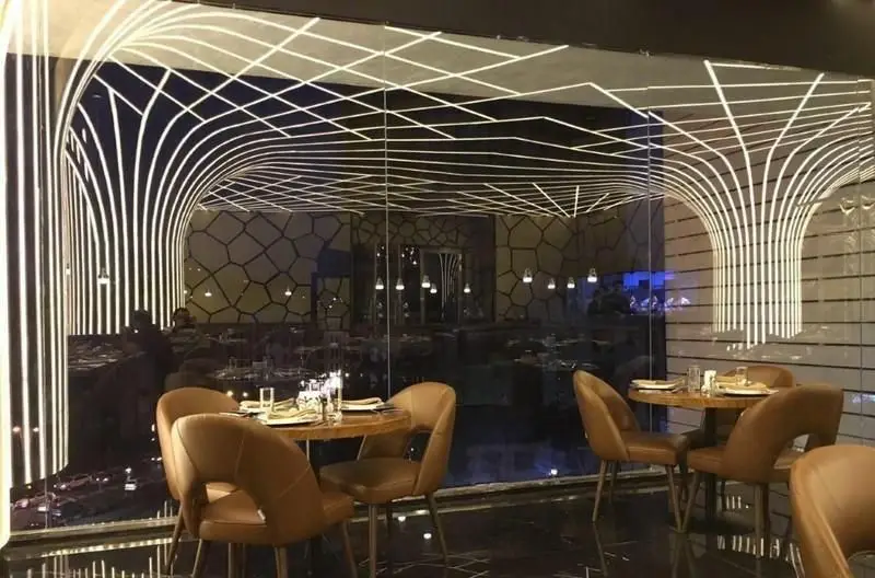 تصویری از طراحی داخلی مدرن و جذاب رستوران اکسون با نورپردازی هنری خطوط سفید و میز و صندلی‌های چوبی شیک آماده پذیرایی.