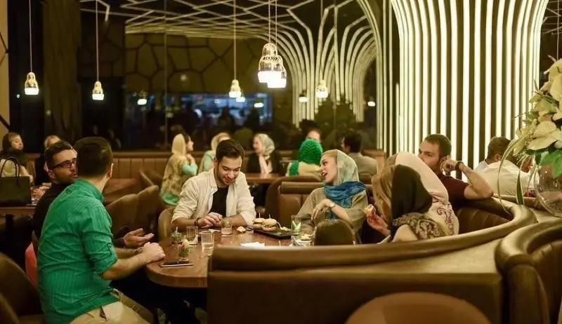 تصویری زیبا از مشتریان شاد در محیط دلنشین و دکوراسیون مدرن رستوران اکسون، مناسب برای تجربه غذاهای عالی و دورهمی‌های دوستانه.