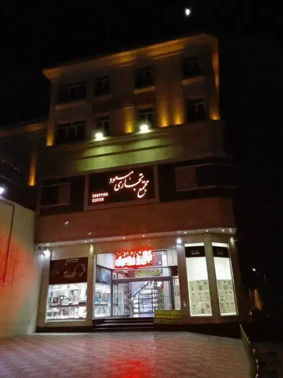 تصویر باکیفیت از ساختمان مجتمع تجاری مسعود و کافی نت رضا در شب با نورپردازی جذاب و ماه در آسمان.