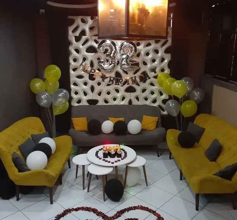 دکوراسیون شیک و اختصاصی کافه ژوانی برای جشن تولد 32 سالگی. فضای دلنشین با مبلمان راحتی زرد و طوسی، بالون، کیک و تزئینات رومانتیک.