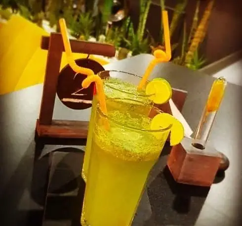 سه لیوان لیموناد خنک و گوارا با تزئین لیمو و نی‌های خاص در کافه ژوانی، فضایی دلپذیر برای لذت‌بردن از نوشیدنی.