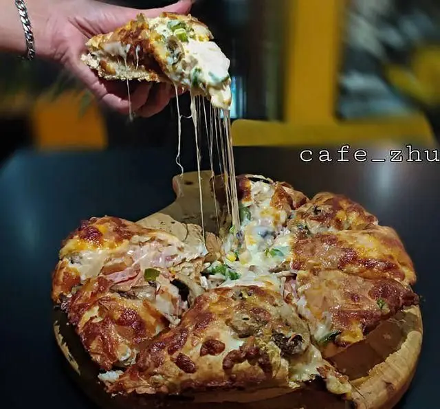 پیتزای پرپنیر و وسوسه‌انگیز کافه ژوانی با پنیر کش‌دار فوق‌العاده بلند. برش پیتزای آمریکایی با تاپینگ‌های متنوع و کراست طلایی در رستوران ژوانی.