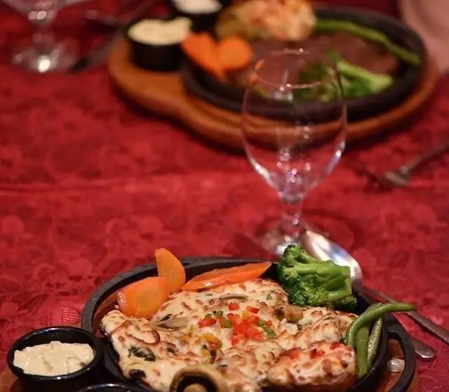 نمایی جذاب از دو سینی غذای خوشمزه شامل استیک و غذای پنیری با سبزیجات متنوع در رستوران لوکس طهران پاریس برای شام یا ناهار.