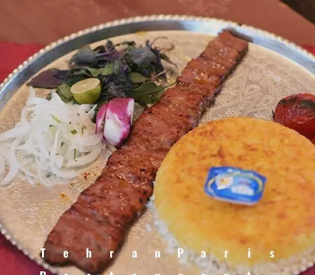 عکس کباب کوبیده اصیل ایرانی با برنج زعفرانی و ته دیگ طلایی، سبزیجات تازه، گوجه و پیاز در رستوران طهران پاریس.