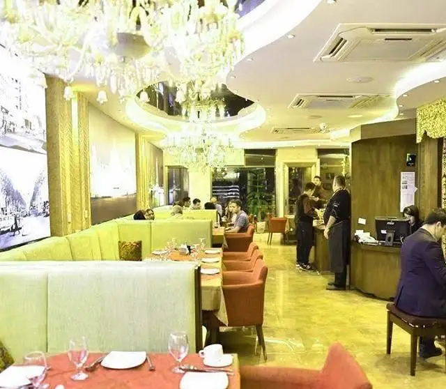 فضای داخلی رستوران طهران پاریس با دکوراسیون لوکس و شیک، شامل میز و صندلی‌های راحت و لوسترهای کریستالی در فضایی دلنشین.