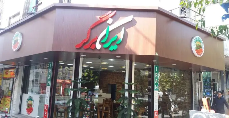 تصویری از نمای بیرونی فست فود ایران برگر، شامل تابلوی بزرگ و جذاب با حروف برجسته و رنگ‌های قرمز، سفید و سبز.
