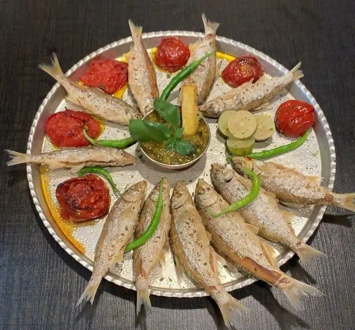 سینی باشکوه ماهی‌های سفید سرخ‌شده با گوجه‌های کبابی و لیمو تازه، از منوی لذیذ دریایی رستوران هانی. تجربه‌ای از غذای اصیل ایرانی.