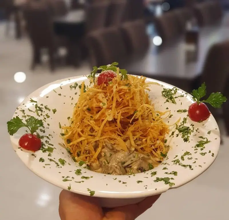 غذای خاص رستوران هانی: خوراک مرغ و قارچ با سس خامه‌ای و سیب‌زمینی‌های چیپسی و ترد، سرو شده برای تجربه‌ای دلنشین.