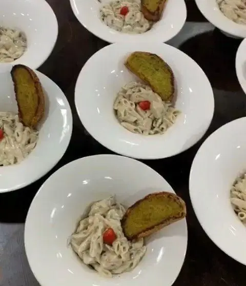 پاستا آلفردو خامه ای رستوران هانی با نان سیر برشته و گوجه گیلاسی. غذای ایتالیایی خوش طعم در کاسه های سفید شیک.