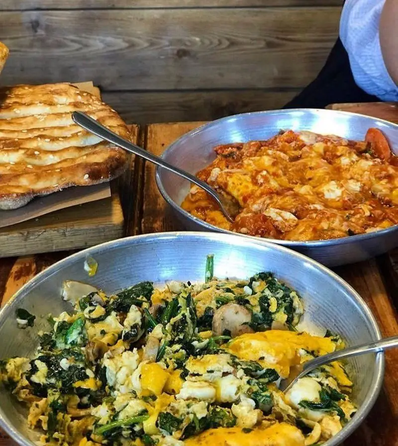 میز صبحانه رستوران برادران: املت مخصوص با اسفناج و قارچ، املت گوجه و نان بربری تازه. یک وعده غذایی کامل و مقوی.