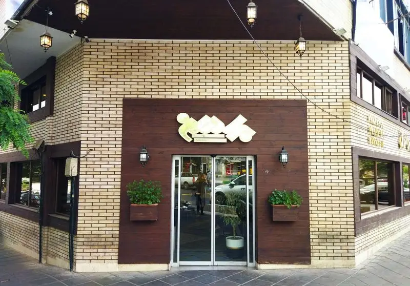 نمای بیرونی رستوران برادران با نمای آجری روشن، پنل‌های چوبی تیره، در ورودی شیشه‌ای و گلدان‌های سبز، فضایی دلنشین.