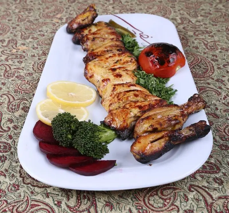 تصویری از جوجه کباب ممتاز رستوران سفیر: شامل تکه‌های مرغ گریل‌شده، ساق مرغ کبابی، گوجه، لیمو و سبزیجات تازه. تجربه‌ای لذیذ از غذای ایرانی.