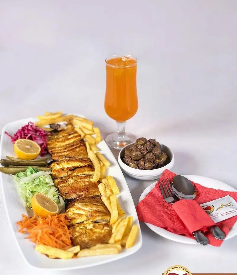 غذای اصلی رستوران سفیر شامل فیله مرغ گریل، سیب زمینی سرخ کرده، سالاد، لیمو و ترشی، همراه با آب پرتقال. تجربه‌ای لذیذ و کامل.