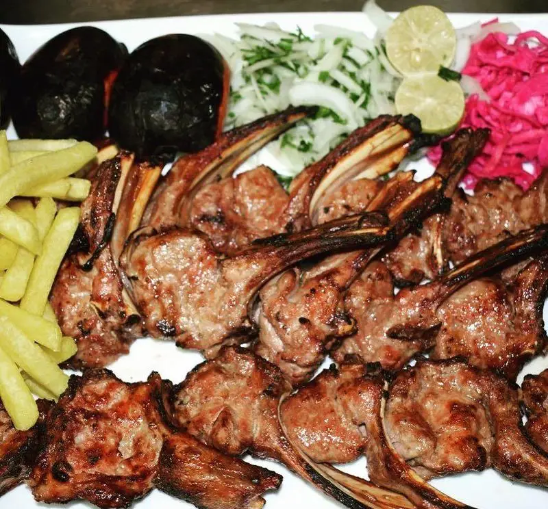 شیشلیک آبدار و کباب لذیذ رستوران سفیر با دورچین کامل شامل سیب‌زمینی، گوجه، پیاز، سبزیجات و ترشی؛ غذای اصیل ایرانی.