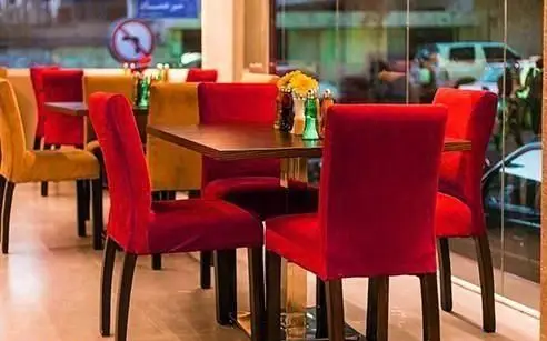 نمایی دلنشین از فضای داخلی رستوران ایرانی میر عماد با میز و صندلی های قرمز و زرد، مناسب برای تجربه یک غذای لذیذ و دلپذیر.