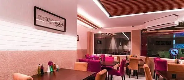 نمایی از دکوراسیون شیک و فضای داخلی دلنشین رستوران ایرانی میر عماد با میز و صندلی‌های راحت و نقاشی دیواری زیبا.