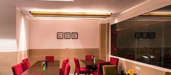 فضای داخلی دنج و مدرن رستوران ایرانی میر عماد با میز و صندلی‌های قرمز شیک، آماده پذیرایی از مشتریان برای تجربه‌ای دلنشین.