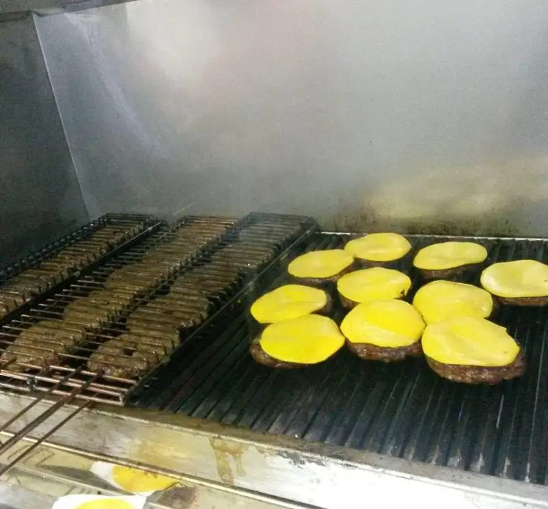 آماده سازی برگرهای خوشمزه هاکوپیان با پنیر ذوب شده روی گریل داغ؛ گریل شدن برگرهای تازه و کباب برای مشتریان.