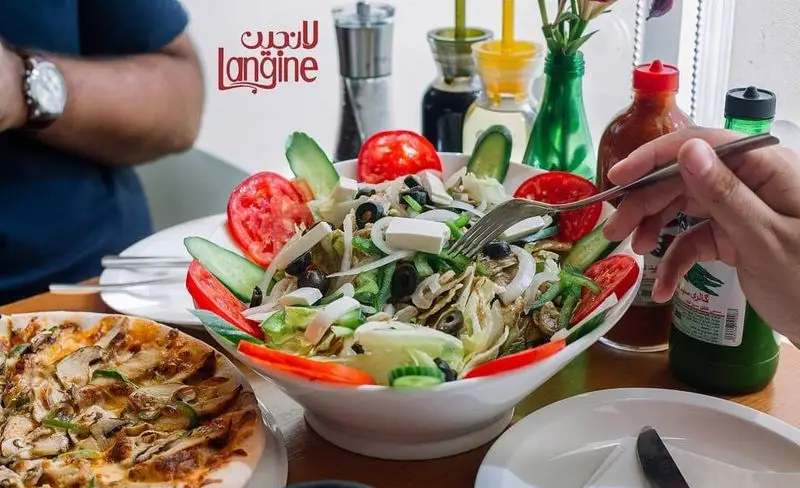 لذت صرف غذا در کافه و رستوران لانجین: سالاد پرملات و پیتزای قارچ تازه، آماده برای مشتریان عزیز در محیطی دلنشین.