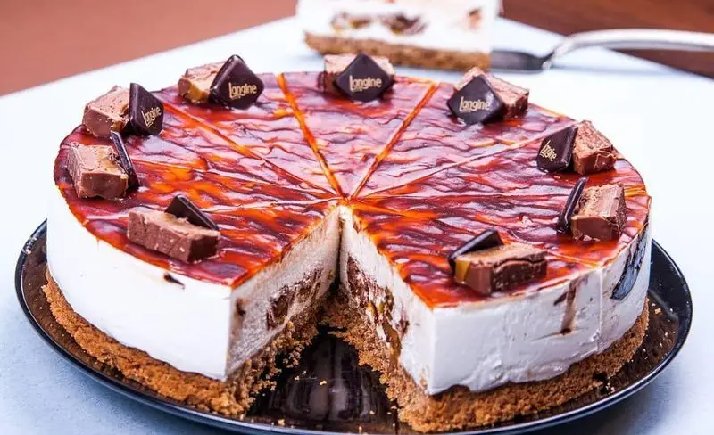 کیک موس لانجین با سس کارامل، برش خورده و آماده سرو در رستوران و کافه لانجین. دسر خوشمزه با پایه بیسکوییت و لایه های کرمی