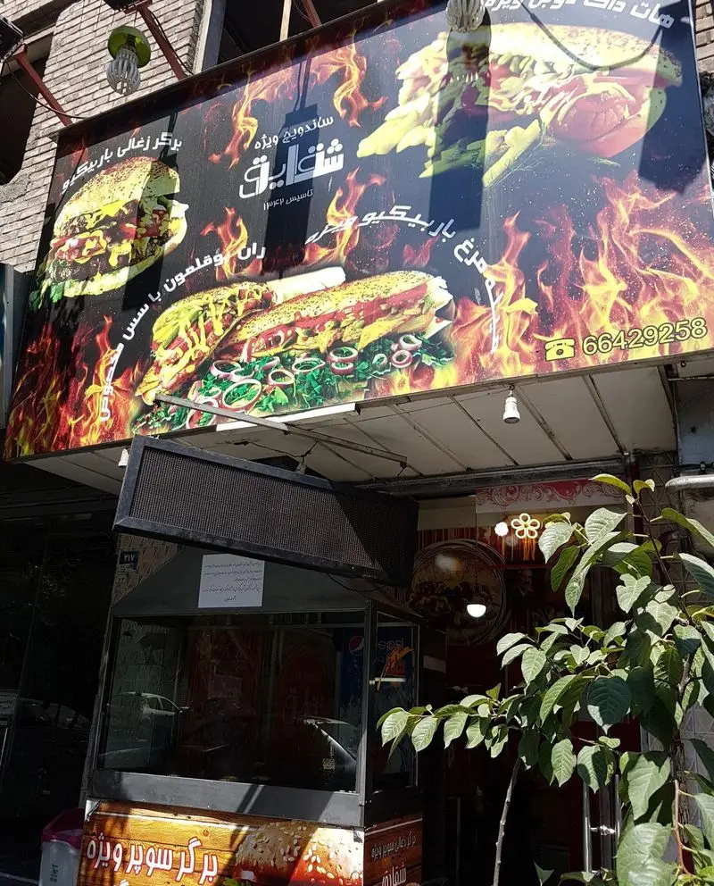 تابلوی رستوران پیتزا برگر شقایق با طرح شعله، شامل عکس برگر زغالی و ساندویچ ویژه، شماره تماس و سال تاسیس ۱۳۶۲.