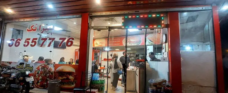 نمای بیرونی رستوران فست فود پیتزا تک در شب با شماره تلفن 36557776، ارائه دهنده انواع پیتزا، همبرگر و غذای آماده
