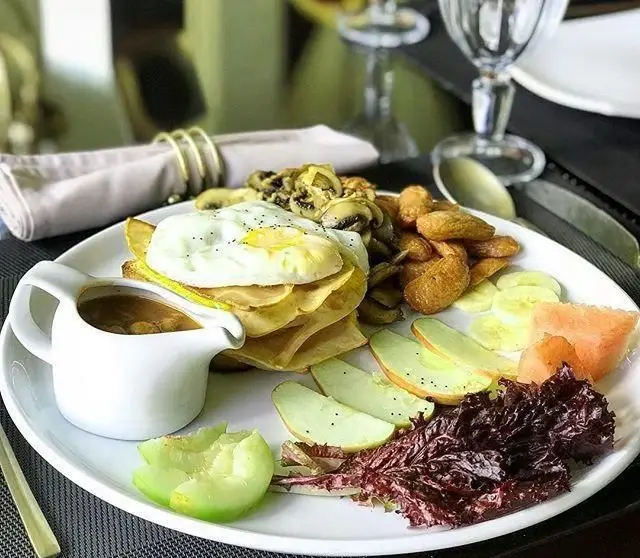 بشقاب صبحانه کامل و جذاب کافه هفت شامل پنکیک، تخم مرغ، قارچ، سیب زمینی، میوه تازه و سس مخصوص. مناسب برای شروع روزی پرانرژی.