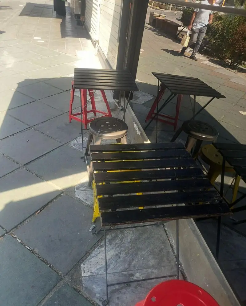 میز و صندلی‌های فضای باز فست فود اُ ...اینو! در پیاده‌رو، آماده پذیرایی از مشتریان برای تجربه غذایی دلپذیر و دنج.