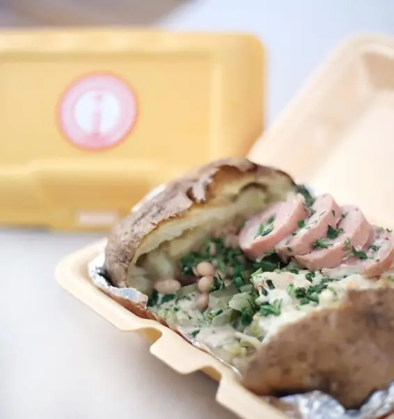 سیب‌زمینی تنوری (جکت پتیتو) گرم و لذیذ با مغز پر از سوسیس، لوبیا، سس مخصوص و سبزیجات تازه از فست فود اُ ...اینو! آماده سرو در ظرف.