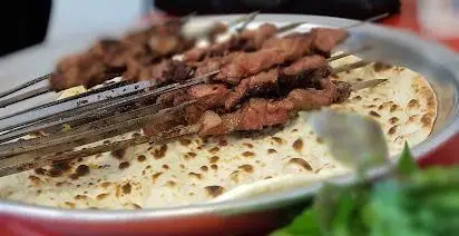 نمایی نزدیک از کباب جگر تازه و لذیذ، سرو شده روی نان داغ در رستوران ایرانی جگرکی توچال، یک تجربه غذایی اصیل و خوشمزه.