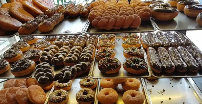 تصویر ویترین جذاب نان و پیراشکی بهمن، نمایشگر انواع پیراشکی، دونات‌های شکلاتی، ساده و رنگارنگ تازه و خوشمزه.