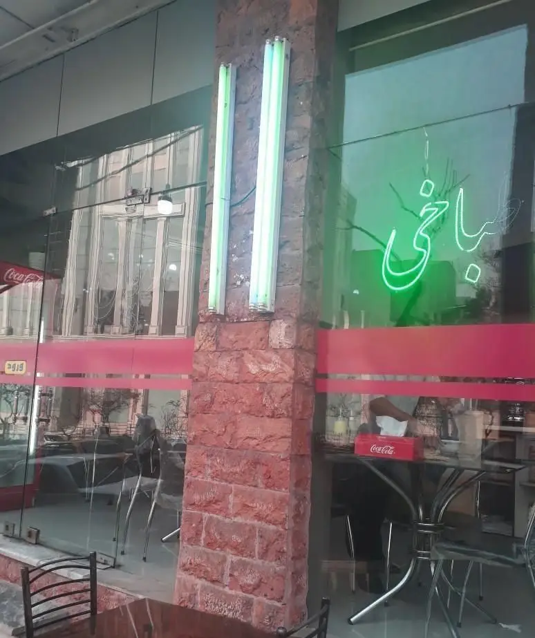 نمای بیرونی طباخی توچال با تابلوی نئون سبز، ورودی شیشه‌ای و ستون آجری. محیطی دلنشین برای صبحانه و کله‌پاچه.