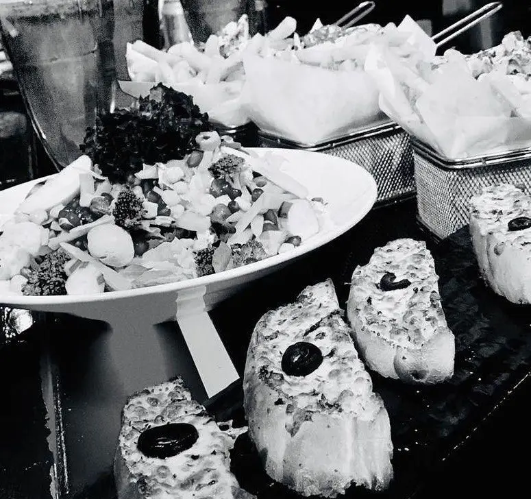 تصویری از منوی متنوع پیتزا نایت شامل سالاد فصل تازه، نان سیر و پنیر خوش‌طعم، و سیب‌زمینی سرخ‌کرده طلایی.