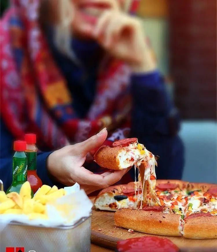 برش پیتزای نایت با پنیر فوق‌العاده کش‌دار و خوشمزه، به همراه سیب‌زمینی سرخ‌کرده. لذت یک غذای فست‌فودی عالی در رستوران نایت.