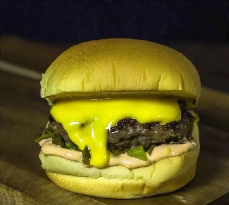 تصویری از همبرگر لذیذ دیزلی برگر با پنیر چدار طلایی و ذوب شده روی گوشت آبدار و سس مخصوص، ظاهری بسیار اشتهابرانگیز.