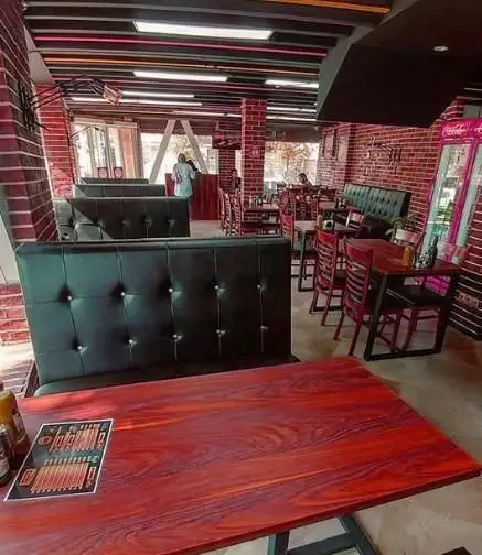 دکوراسیون داخلی دیزلی برگر با صندلی های راحتی مشکی، میزهای چوبی زیبا و فضای دلنشین فست فود برای مشتریان.