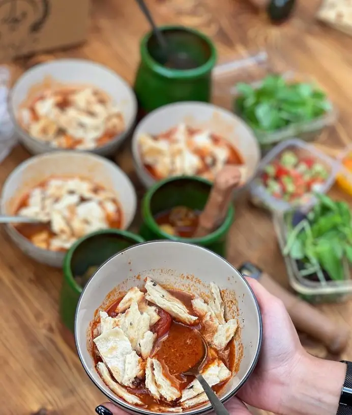 چند کاسه دیزی لذید رستوران دیزی دیدار همراه با نان تکه شده، سبزی و سالاد تازه. غذای سنتی ایرانی در فضایی دلنشین.