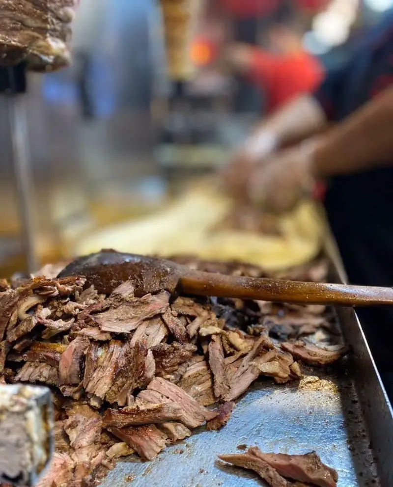 گوشت شاورما تازه برش خورده و لذیذ فست فود یاس روی سینی آماده سرو. تهیه غذای خوشمزه و داغ شاورما و کباب ترکی.