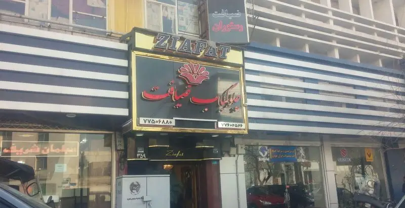 نمای اصلی و ورودی چلوکبابی ضیافت با تابلوی بزرگ "ZIAFAT" و نام "ضیافت" به فارسی، همراه با شماره‌های تماس و معماری ساختمان.